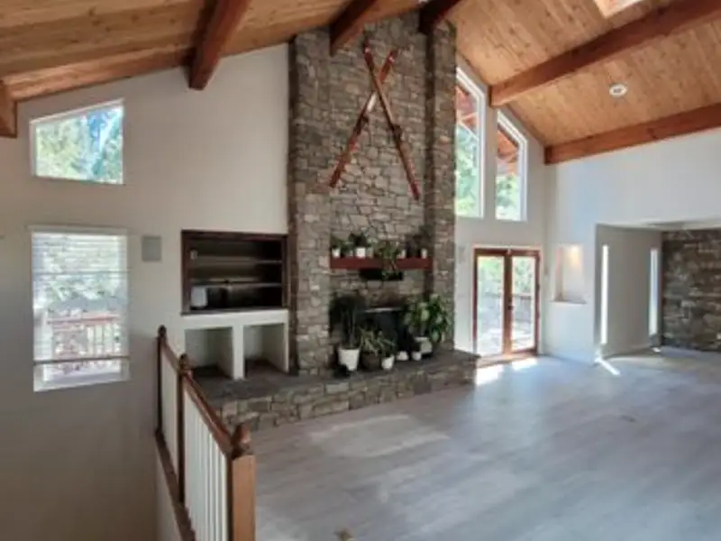 Vaulted living room with wood-beam ceiling and stone fireplace